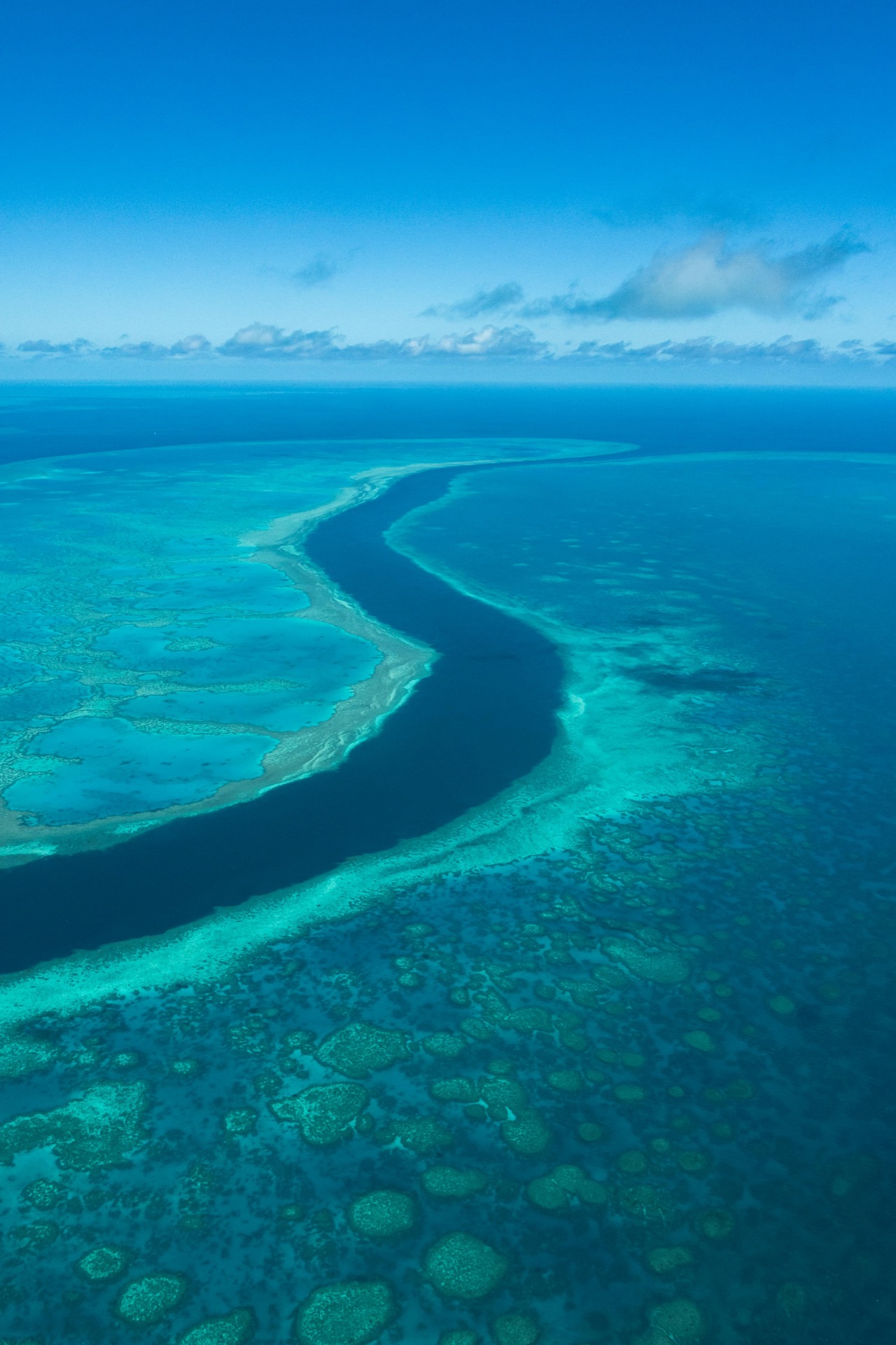 Vista aérea de un canal de arrecife abriéndose paso en aguas turquesa